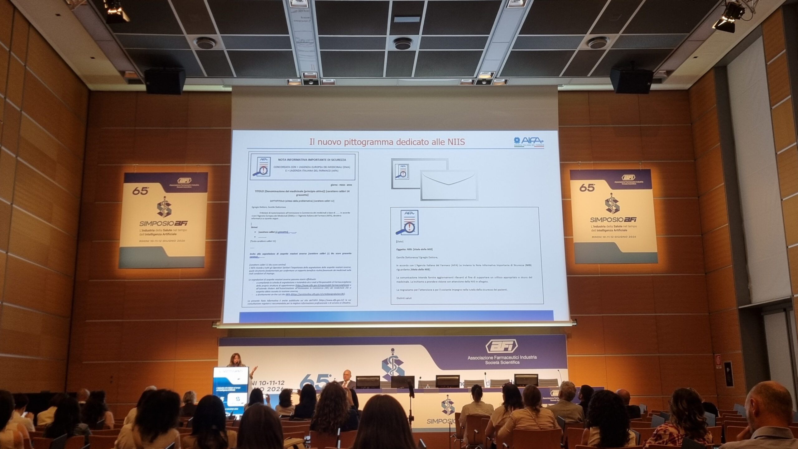 Nuovo Pittogramma AIFA per NIIS Simposio AFI 2026 Posizionamento Nuovo Pittogramma Foto della sessione farmacovigilanza AFI 2026. Dottoressa Sottosanti che illustra dove verrà posizionato il nuovo pittogramma AIFA nelle NIIS